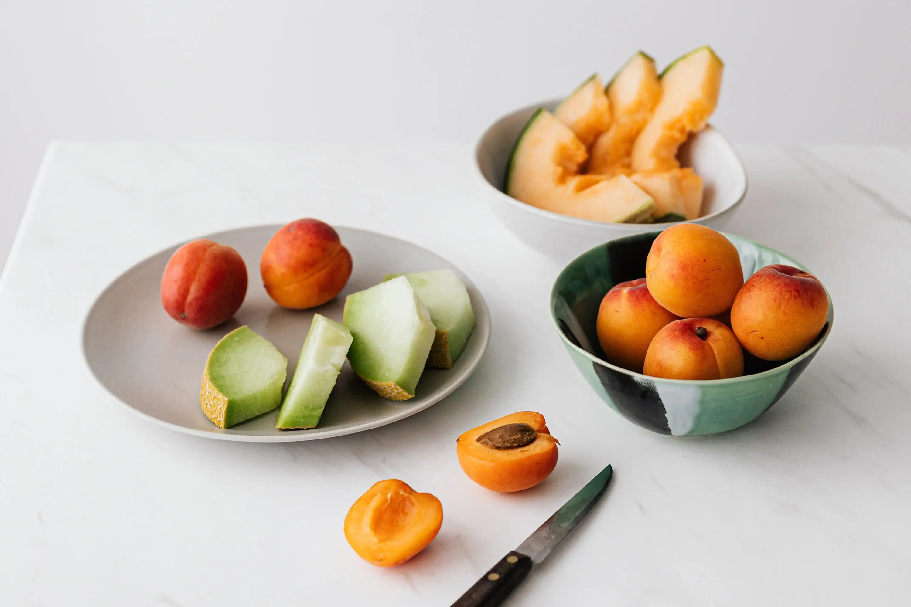 a plate and two bowls of fresh fruit